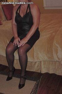 Wife in black minidress and gartered hose and heels, at a bed & breakfast o...
